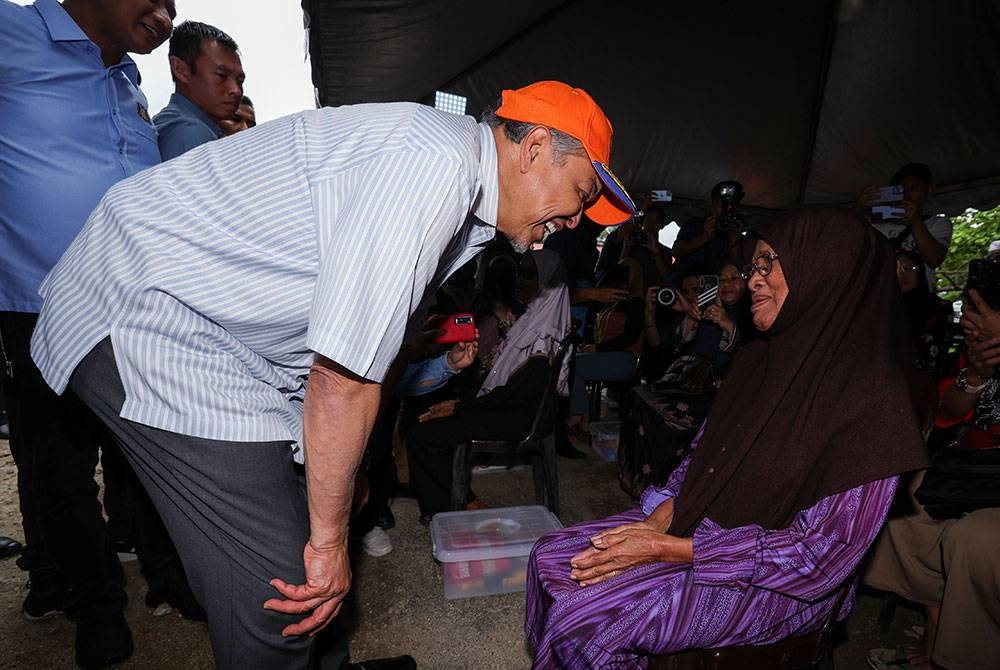 Ahmad Zahid beramah mesra bersama mangsa banjir, Katimah Kadni, 78, ketika mengadakan lawatan ke Pusat Pemindahan Sementara Sekolah Kebangsaan Seri Sejati hari ini. - Foto Bernama