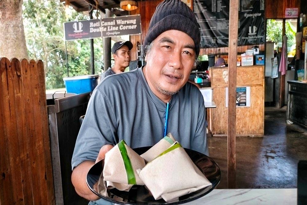 Baharam menunjukkan nasi lemak RM1 yang dijual di warung kedainya di Batu 8, Gangsa Durian Tunggal.