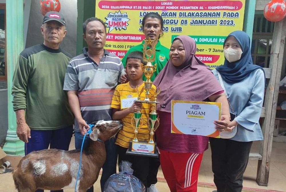 Chesta Khadafi membawa pulang piala dan kambing selepas menjuarai pertandingan lato-lato di Sidoarjo baru-baru ini. - Agensi