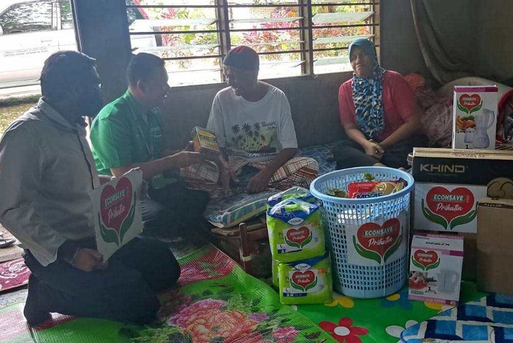 Zamzuri (dua kiri) menyantuni Hashim dan keluarganya di Desa Keda Batu 13 Pokok Sena baru-baru ini.