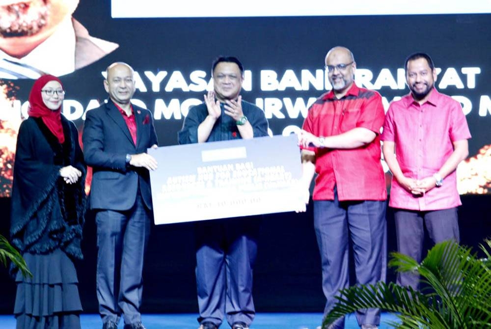 Mohd Irwan (dua dari kanan) menyerahkan mock cek Program Autism Hub for Education Resources & Training (A-Heart) kepada Prof Dr Zaliman (dua dari kiri) disaksikan Tuanku Syed Faizuddin.