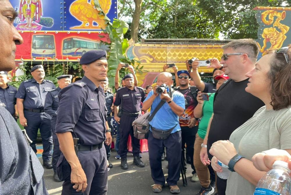 Mohd Shuhaily berbual dengan pelancong asing yang turut menyaksikan perarakan sempena perayaan Thaipusam di Jalan Kebun Bunga.