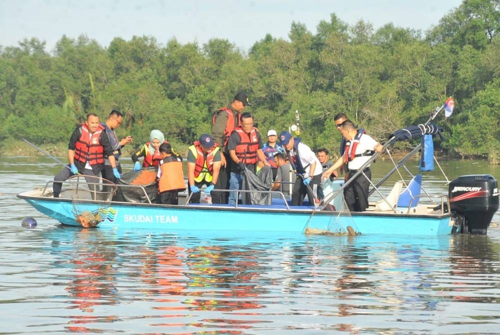 Onn Hafiz (dua, kanan), mengaut longgokan sampah ketika menyertai program berkenaan di Sungai Skudai, pada Ahad.