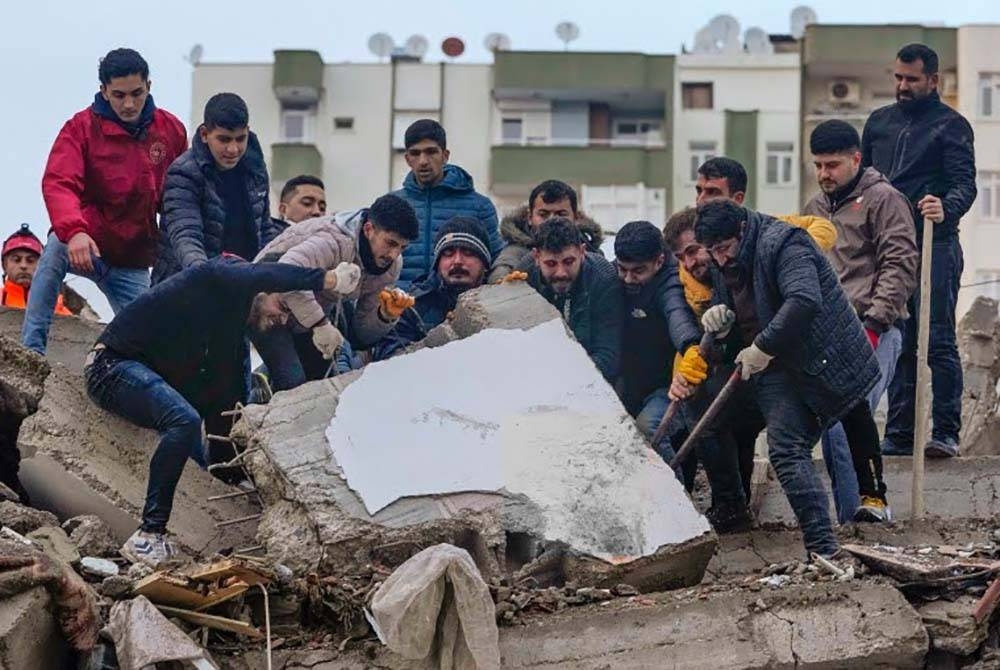 Penduduk berusaha mencari mangsa yang mungkin yerperangkap di bawah sisa runtuhan di Adana, Turkiye. - Agensi