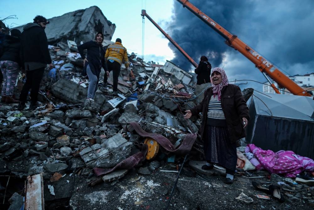 Seorang wanita sebak melihat anggota penyelamat menjalankan operasi mencari dan menyelamat di tapak bangunan runtuh berikutan gempa bumi di Iskenderun, daerah Hatay, Turkiye. - Foto EPA