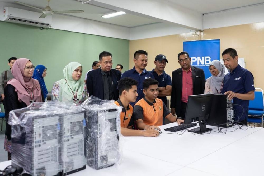 Para pelajar sedang mencuba komputer yang disumbangkan oleh PNB.