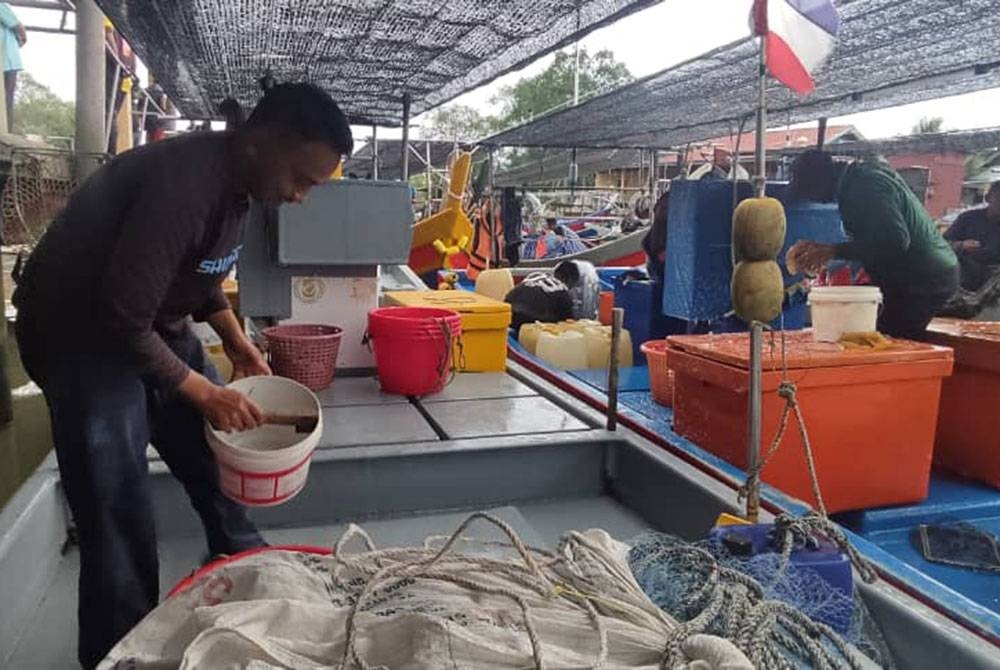 Mohd Aiman mencuci bot selepas pulang menangkap ikan di Pasar Nelayan Seberang Kota, Kubang Rotan, Kuala Kedah.