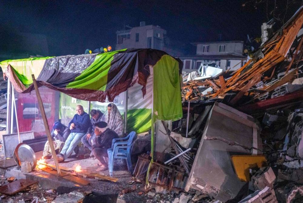 Sebuah keluarga memanaskan diri di dalam khemah selepas kediaman mereka ranap dalam kejadian gemoa bumi di Hatay, Turkiye. - Agensi