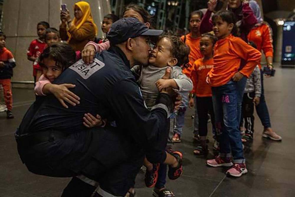 Mohd Safuan Mohmood memeluk anak-anaknya di KLIA Sepang sebelum berlepas untuk menyertai operasi SAR mangsa gempa bumi di Turkiye malam tadi. - Foto Awani