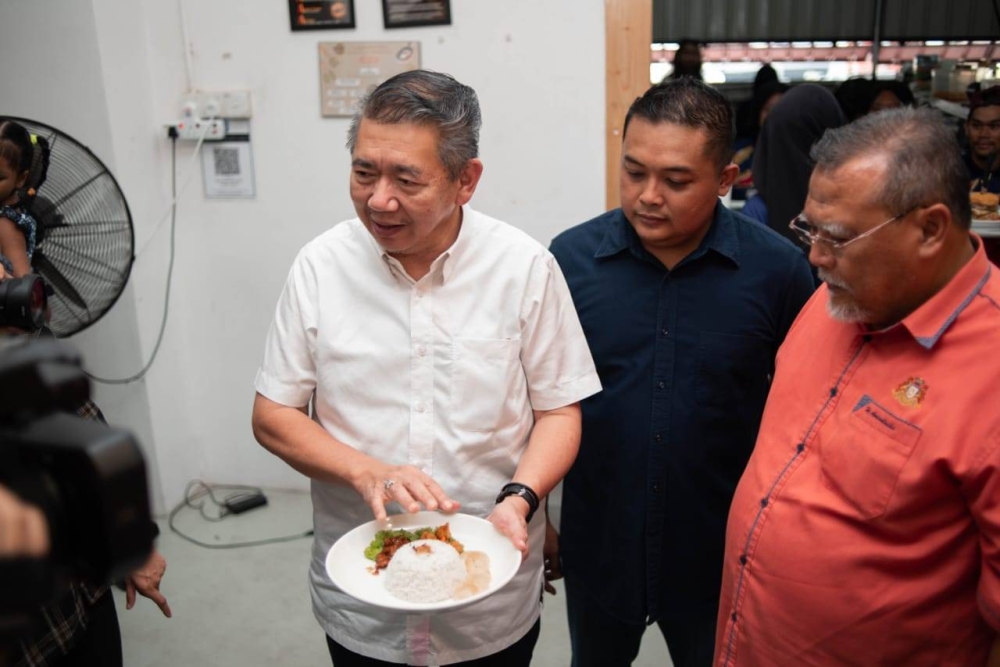 Salahuddin (tengah) dan Aminolhuda (kanan) melihat Menu Rahmah ditawarkan di Wachaa Burger Parit Raja, Batu Pahat pada Khamis. 