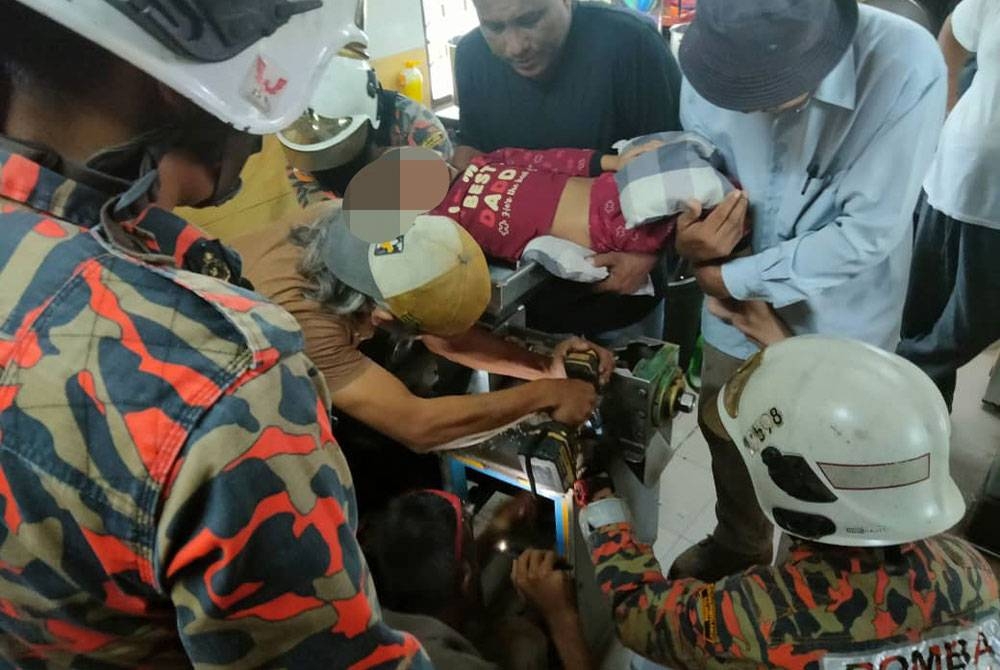 Pasukan bomba berusaha mengeluarkan tangan mangsa yang tersepit pada mesin memproses santan kelapa di Taman Seri Bahagia, Teluk Intan pada Jumaat. - Foto Ihsan Bomba