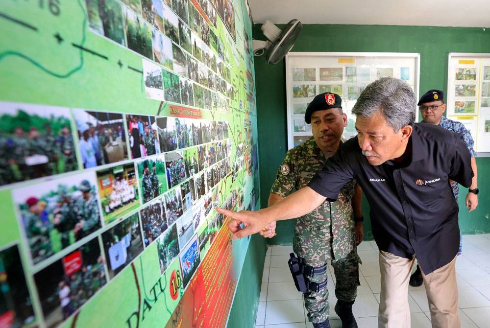 Mohamad bertanya sesuatu mengenai gambar-gambar Ops Daulat kepada Timbalan Komander Esscom, Brigadier Jeneral Johari Ismail (kiri) yang dipamerkan di galeri pameran ketika mengadakan lawatan kerja di Pos Kampung Tanduo pada Jumaat. - Foto Bernama