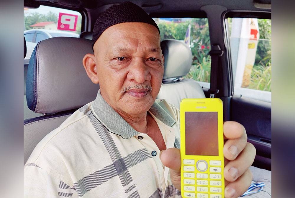 Mohd Yunus menunjukkan telefon bimbit biasa digunakannya tanpa mempunyai rangkaian internet.