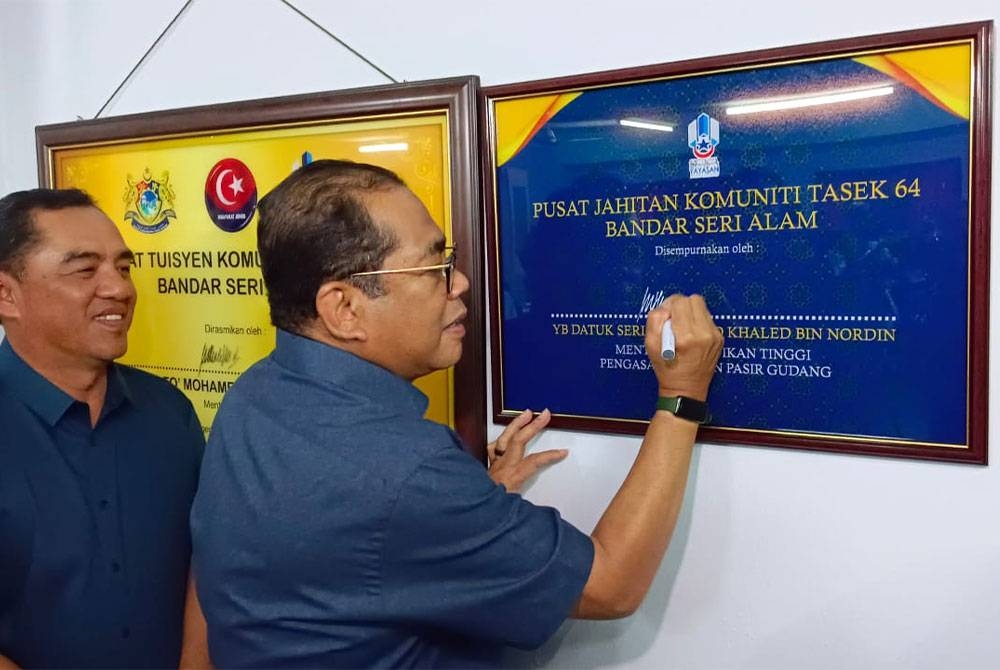 Mohamed Khaled (kanan) diringi Ahli Dewan Undangan Negeri (ADUN) Permas, Baharudin Mohamed Taib menandatangani plak sebagai simbolik merasmikan Pusat Jahitan Komuniti Tasek 64 di Bandar Seri Alam, Pasir Gudang, pada Sabtu.