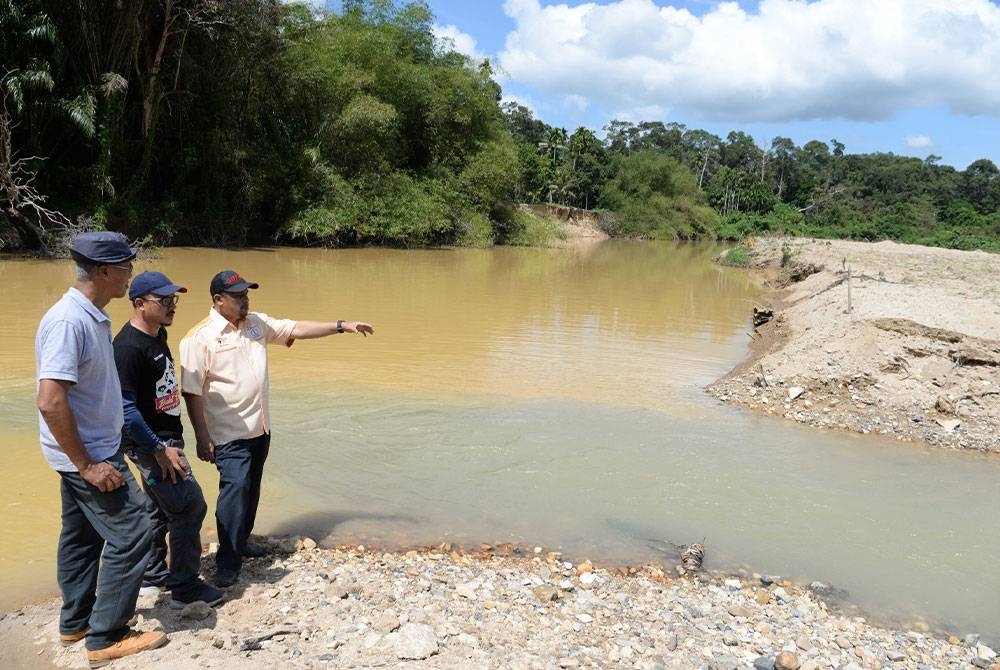 Dari kanan Mahadzir dan Mohd Sobree meninjau keadaan di Sungai Jeneri yang turut berubah warna dan didakwa berpunca daripada kegiatan perlombongan REE.