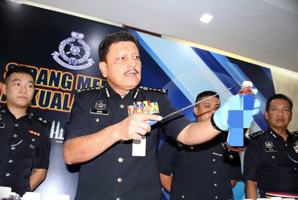 Azmi menunjukkan minuman disyaki berisi dadah yang dirampas dalam serbuan polis, baru-baru ini. - Foto Polis KL