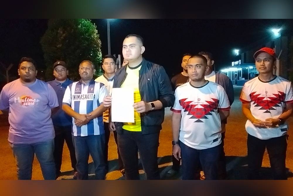 Muhamad Akmal (tiga dari kiri) menunjukkan laporan polis yang dibuat di Balai Polis Merlimau pada malam Isnin.