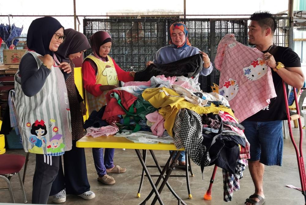 Khairul Faideli (kanan) dibantu Rosila (dua dari kanan) ketika menjual apron bundle di sebuah kedai makan di Kuala Terengganu.