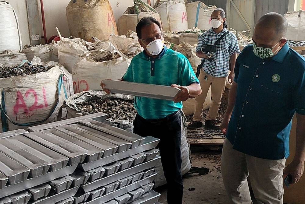 Andansura (depan) menunjukkan jongkong aluminium siap diproses yang ditemui hasil pemeriksaan ke atas sebuah kilang di Kawasan Perindustrian Gebeng di Kuantan pada Selasa.