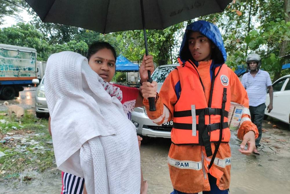 Seorang wanita bersama bayinya dipindahkan ke Dewan Kampung Samy, Tapah berikutan rumahnya dinaiki air. Foto Ihsan APM