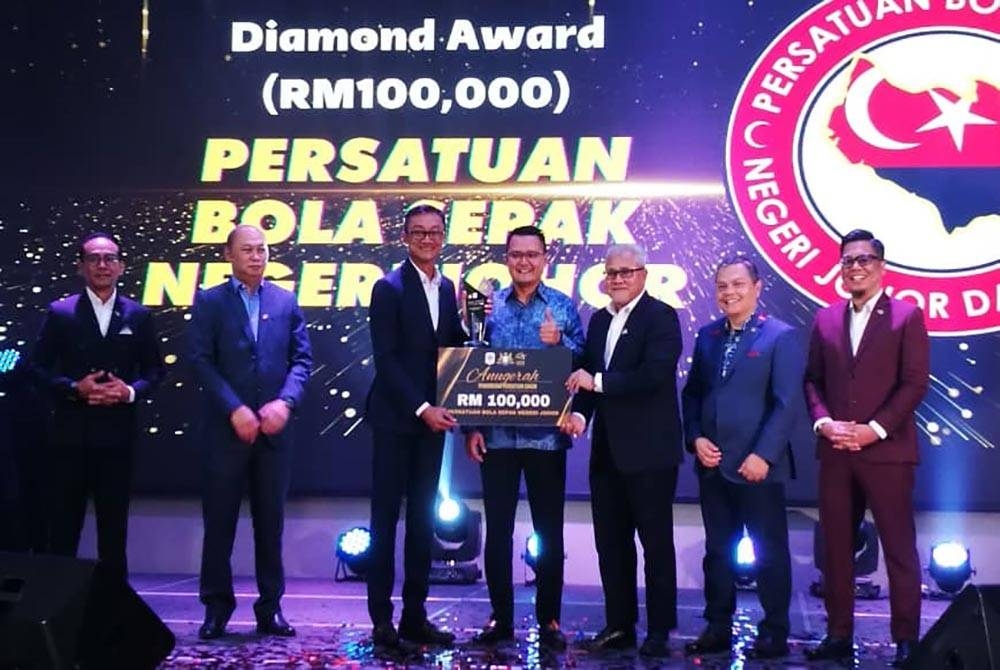 Mohd Hairi (empat dari kanan), menyampaikan Anugerah Geran A kepada Setiausaha Kehormat Persatuan Bola Sepak Johor (PBNJ), Mohd Anizam Jamian pada majlis berkenaan.