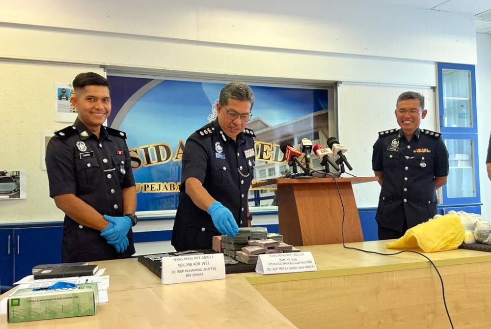 Ismail (tengah) menunjukkan sebahagian wang tunai yang dirampas pada sidang media di IPD Batu Pahat pada Khamis.