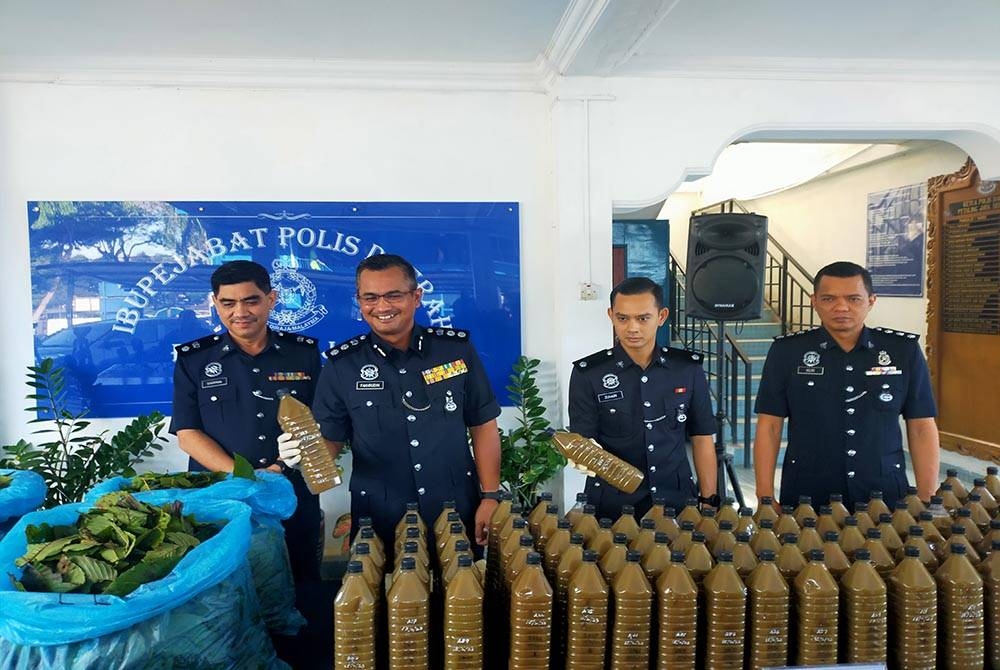 Mohamad Fakhrudin (dua dari kiri) menunjukkan hasil rampasan air ketum selepas pihaknya membuat tangkapan di sebuah rumah di Taman Medan, Petaling Jaya pada Rabu.