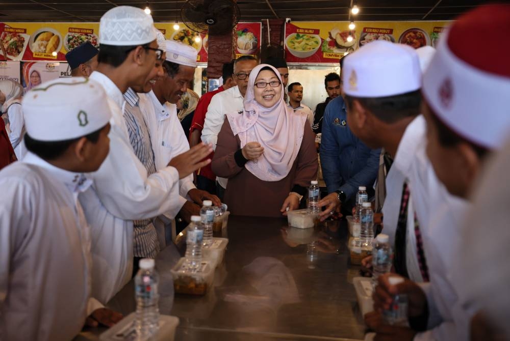 Fuziah Salleh (tengah) bertanyakan sesuatu kepada pelajar yang menikmati menu Rahmah pada Jelajah Menu Rahmah Peringkat Terengganu di sebuah restoran di Kijal pada Jumaat. - Foto Bernama