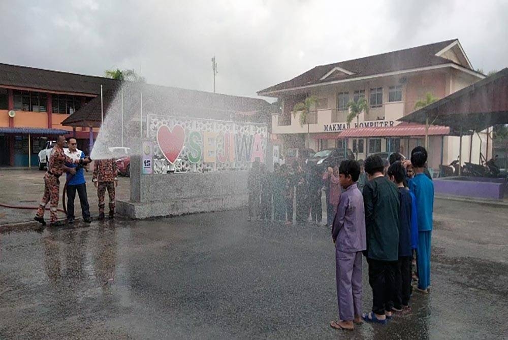 Mohd Faeiz (kiri) dan anggota bomba memandikan kanak-kanak yang menyertai Program Khatan Perdana@Sejiwa pada Sabtu.