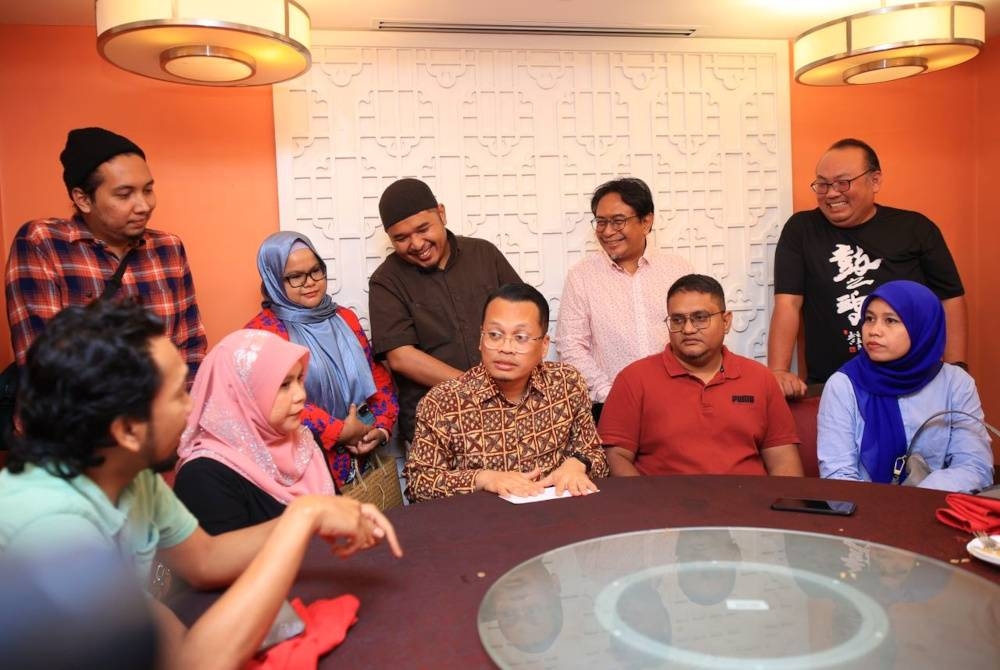 Nik Nazmi (duduk, tiga kanan) beramah mesra dengan pengamal media Kelantan semasa Majlis Makan Malam PKR di Kota Bharu pada Ahad.