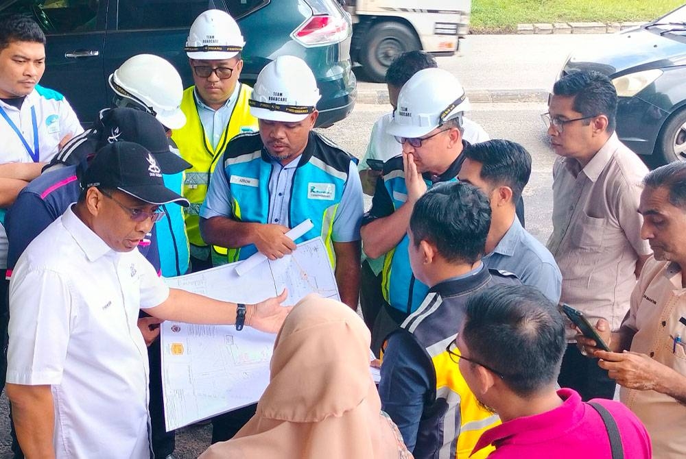 Mohammad Fakhruddin (kiri) sedang melihat pelan jalan yang akan diselenggara oleh pihak berkaitan di Jalan Semambu di sini pada Selasa.