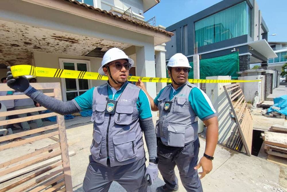 Dua pegawai CIDB Pulau Pinang memasang pita kuning di salah sebuah rumah yang menggunakan khidmat syarikat kontraktor tidak berdaftar dalam operasi bersepadu pada Rabu.