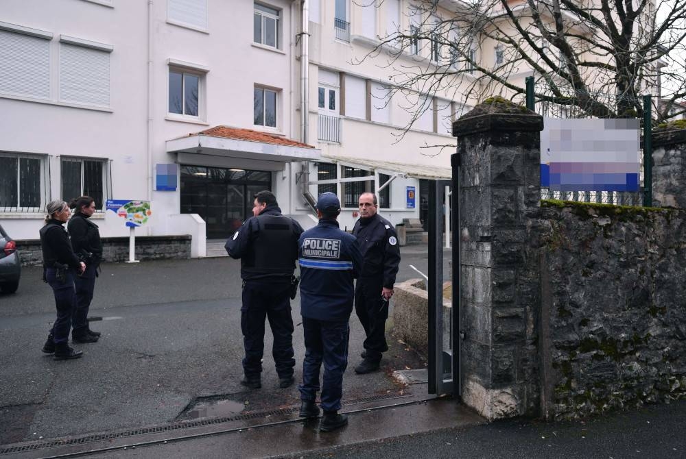 Pegawai polis berdiri di pintu masuk sebuah sekolah menengah di bandar Saint-Jean-de-Luz, Perancis, dalam kejadian seorang guru maut selepas ditikam oleh seorang murid pada Rabu. - Foto AFP