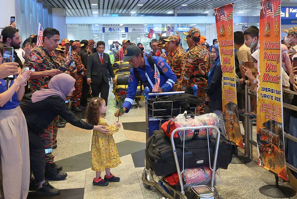 Anak kecil warga Turkiye memberikan sejambak bunga kepada salah seorang anggota penyelamat Malaysia bagi menyambut ketibaan Anggota Kumpulan Kedua (MAS-10) Pasukan SAR di KLIA pada Khamis. - Foto Bernama