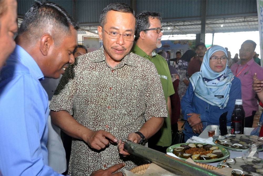 Ahmad Samsuri melihat teknologi memasak lemang menggunakan paip besi di gerai FAMA di Karnival Gedung Pengeluaran Makanan Terengganu 2023 di Sungai Tarom, petang ini. Foto Bernama