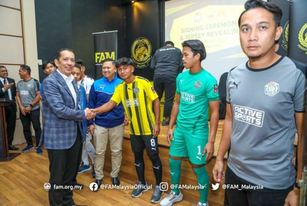 Mohd Joehari (kiri) bersalaman dengan para pemain sambil diperhatikan Noor Zaidi (dua dari kiri) pada majlis menandatangani penajaan jersi Puma buat skuad FAM-MSN. - Foto Facebook FAM