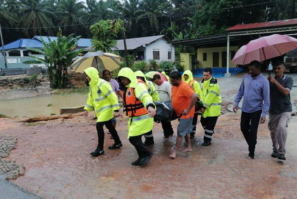 Anggota polis membawa mayat Sarathkumar yang ditemui mati dalam kereta yang di hanyutkan air deras di Jalan GSA Chamek, Paloh, Kluang, pada Rabu