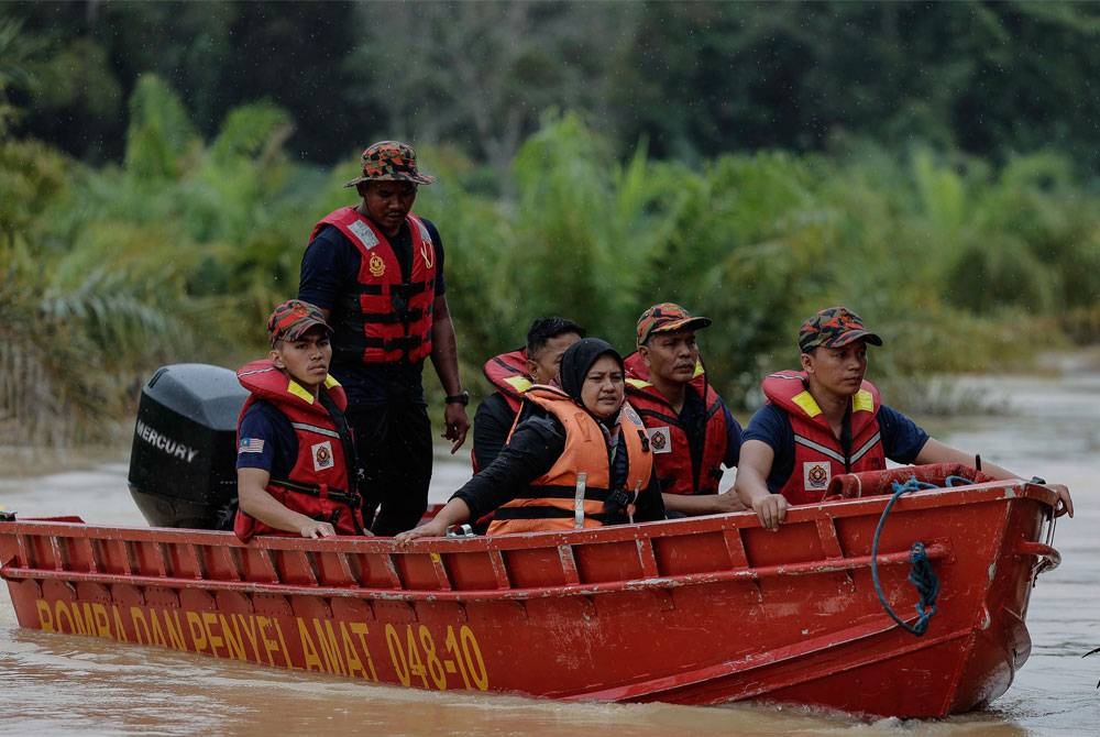 Anggota Balai Bomba dan Penyelamat Bandar Baru Segamat giat membantu mengeluarkan mangsa yang terperangkap selepas banjir melanda beberapa buah Kampung di Jalan Kuala Paya- Balai Badang ketika tinjauan pada Sabtu. - Foto: Bernama