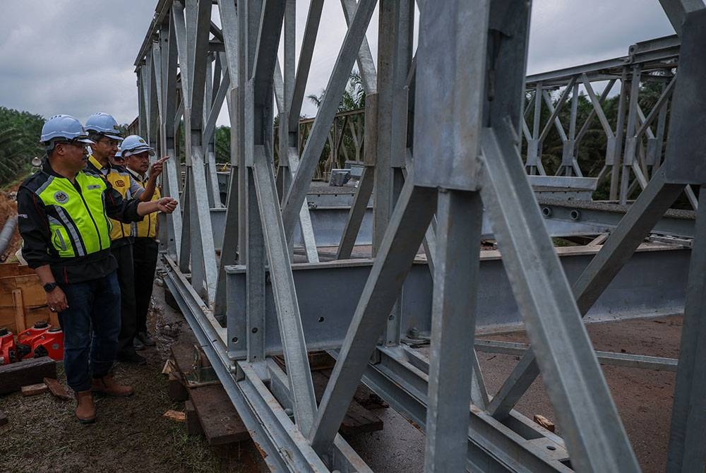 Wan Ahmad (kiri) melihat kerja-kerja pemasangan jambatan bailey di laluan FT2490 Jalan masuk ke Perwira Jaya dan Selancar yang runtuh akibat banjir. - Foto Bernama