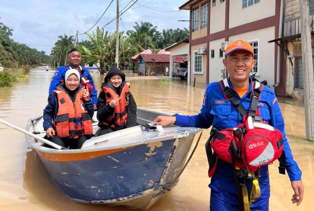 Anggota Pertahanan Awam Malaysia (APM) memindahkan mangsa banjir di Kampung Parit Basri, Batu Pahat.