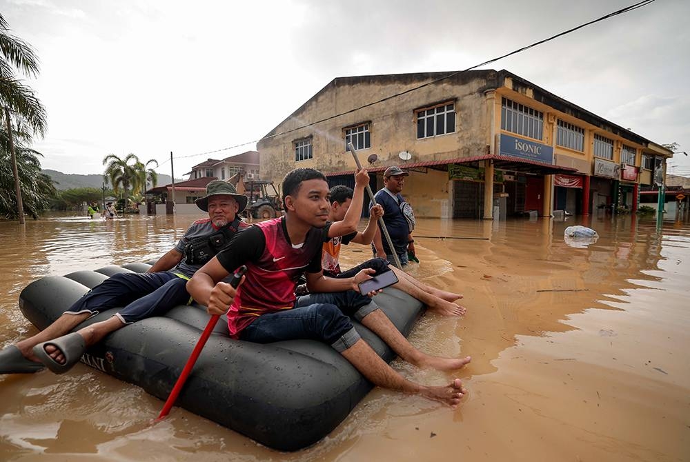 Beberapa penduduk setempat meredah banjir dari kediaman ke PPS ketika tinjauan di Seri Medan Batu Pahat pada Isnin. - Foto Bernama