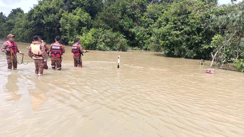 Anggota bomba melakukan operasi mencari dan menyelamat seorang wanita yang hanyut dalam keretanya di Jalan Nitar Utama, Mersing pada Isnin.