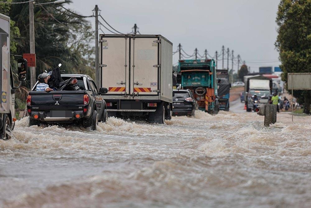 Beberapa kenderaan cuba untuk meredah banjir ketika tinjauan di Jalan Utama Yong Peng ke Muar hari ini.- Foto Bernama