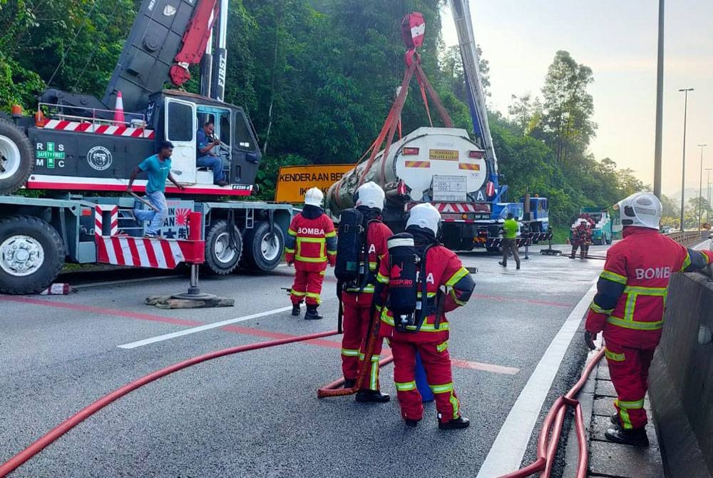 Kerja-kerja pengalihan lori sedang dilakukan dengan bantuan kren. - Foto Bomba Perak