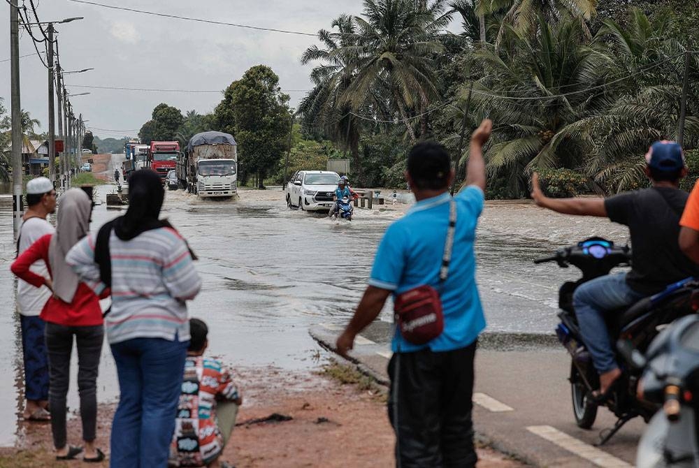 Beberapa kenderaan cuba untuk meredah banjir ketika tinjauan di Jalan Utama Yong Peng ke Muar pada Rabu. - Foto: Bernama