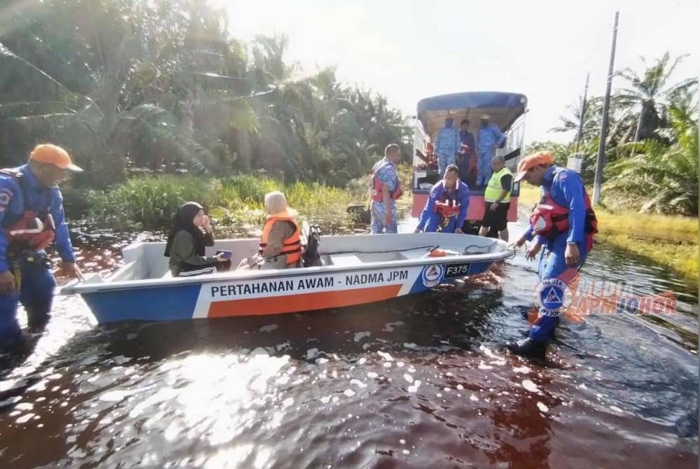 Anggota APM membawa keluar mangsa banjir di Batu Pahat pada Khamis. - Foto APM