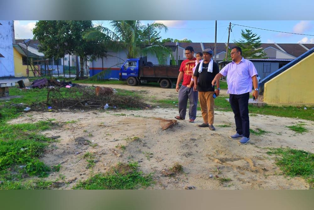 Andansura (kanan) menunjukkan lokasi pokok tumbang yang meragut nyawa anak perempuan Mohamad Hasnizam (tengah) selain menghempap enam kenderaan dalam kejadian di Taman Balok Baru di sini Januari lalu.