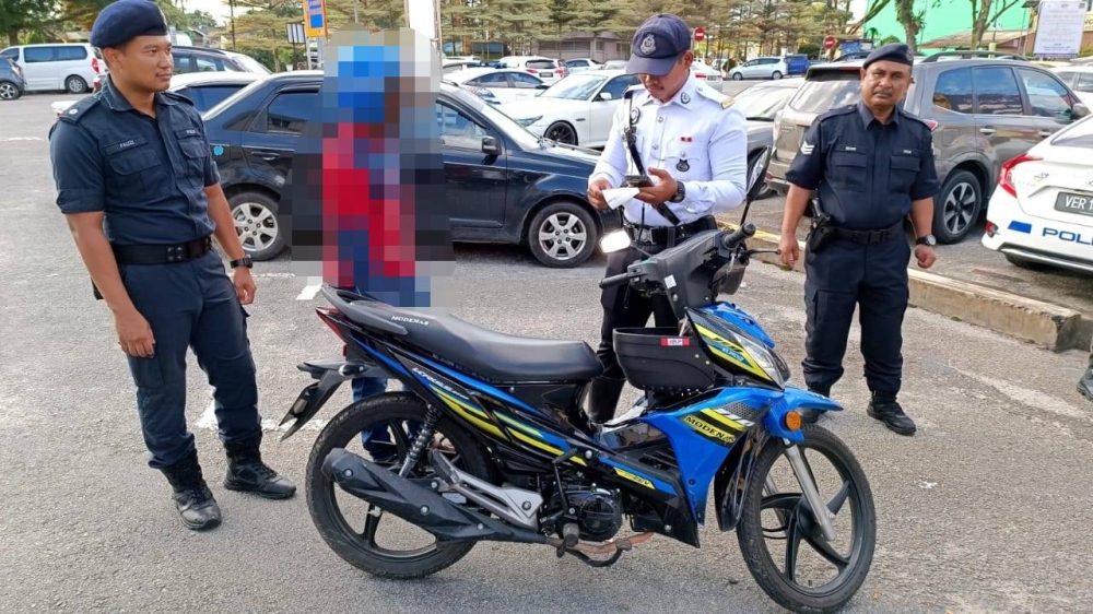 Anggota polis trafik memeriksa lesen memandu seorang pengguna jalan raya dalam operasi dijalankan di sini, pada petang Rabu. 