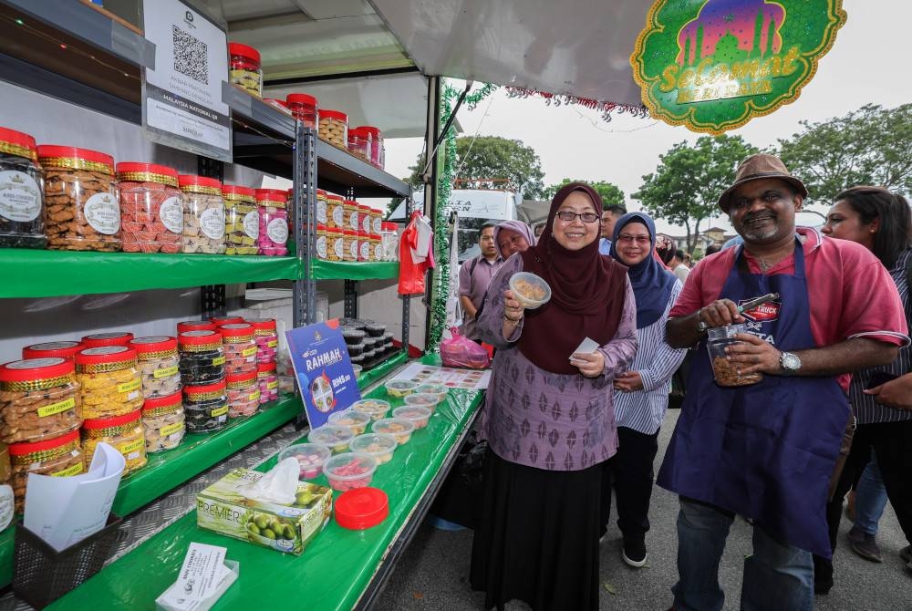 Fuziah (kiri) menunjukkan makanan ditawarkan dengan harga Menu Rahmah pada Pelancaran Fiesta Food Truck Menu Rahmah sempena Program Jualan Rahmah Parlimen Pulai di tempat letak kereta Plaza Angsana hari ini. - Foto Bernama