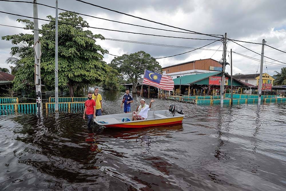 Penduduk setempat menggunakan sampan untuk meredah banjir ketika tinjauan di sekitar Parit Sulong, Batu Pahat hari ini. - Foto Bernama